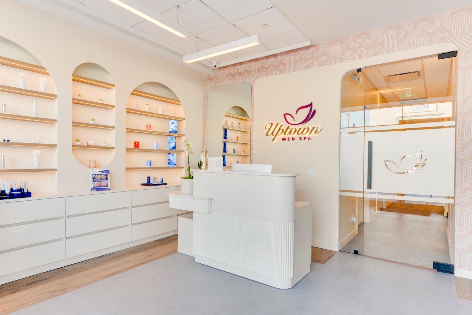 Bright modern spa interior with white shelves and Uptown Med Spa logo.