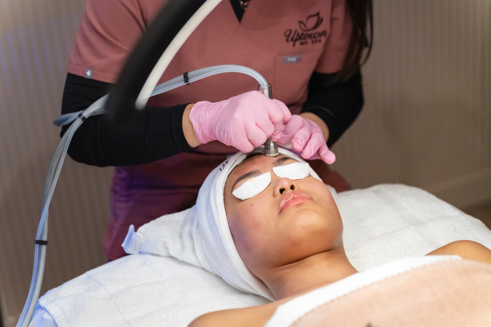 Aesthetician performing hydradermabrasion facial on client